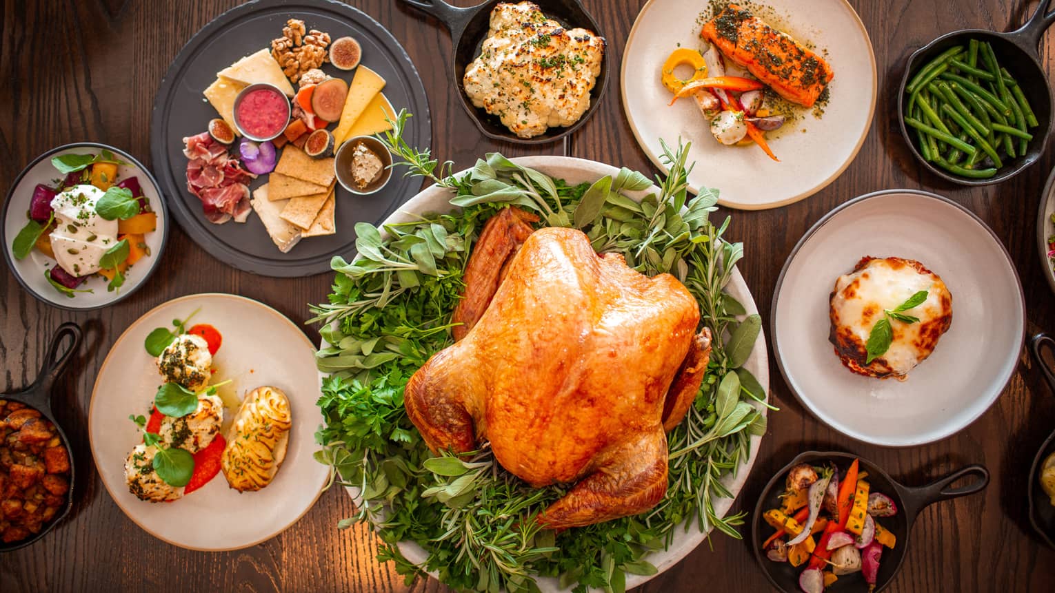 An assortment of thanksgiving food including Turkey, charcuterie, vegetables, and more.
