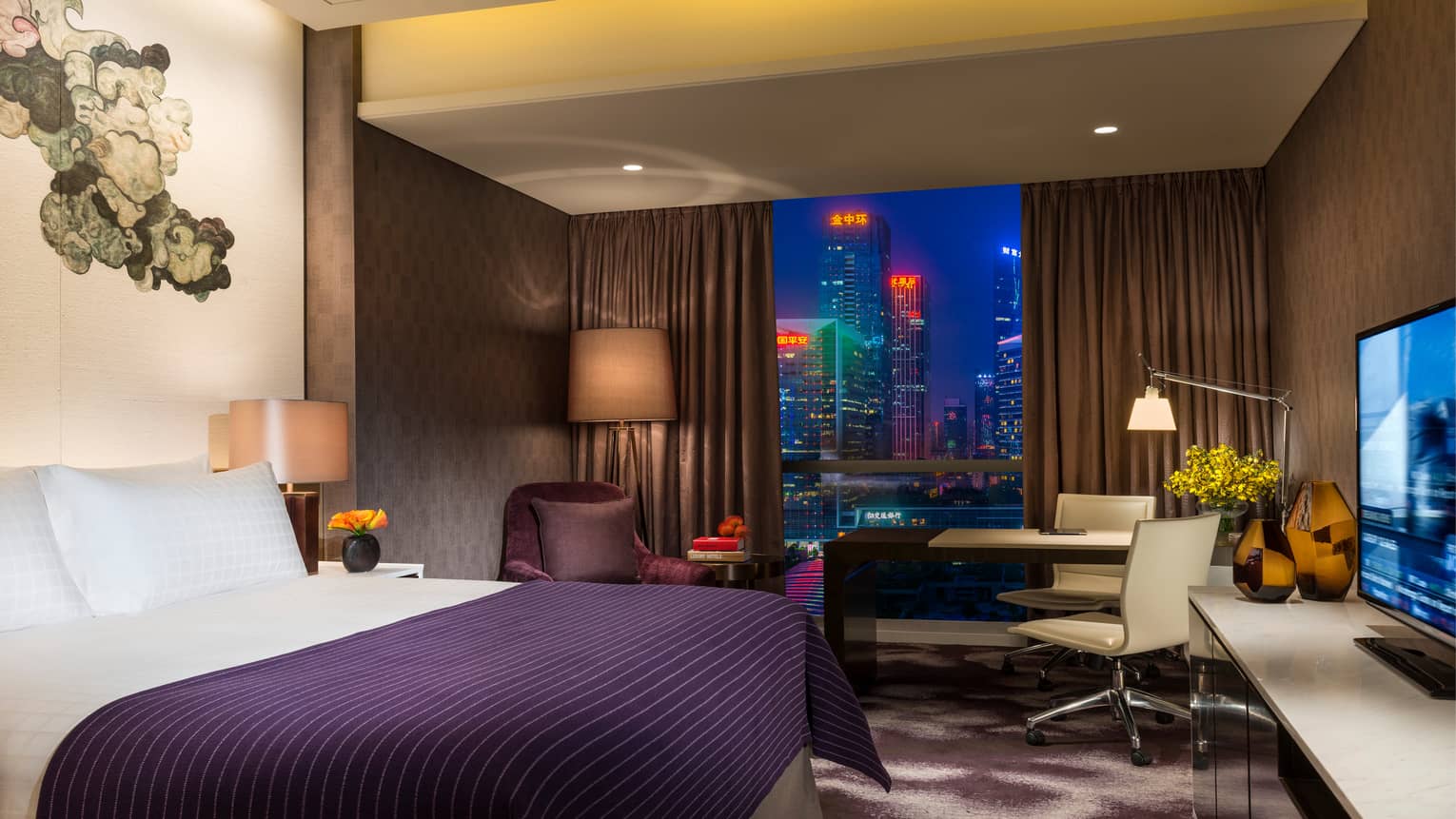 Hotel room bed with purple blanket under black-and-white Chinese brushwork mural