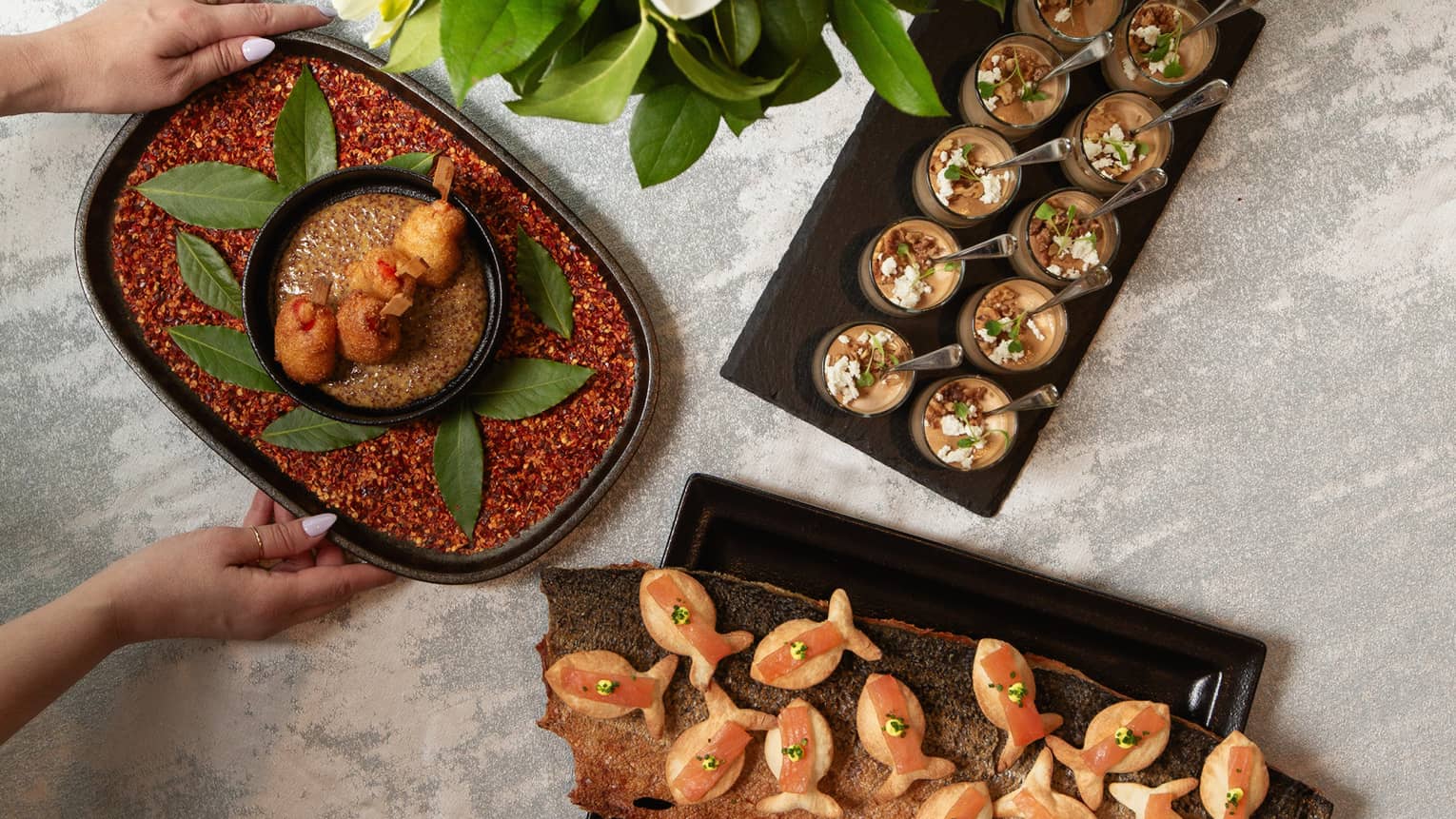 Aerial view of appetizers on trays next to bouquet of white flowers on table