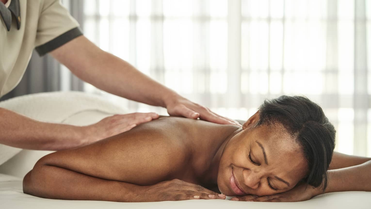 A person getting a massage in a well lit treatment room.