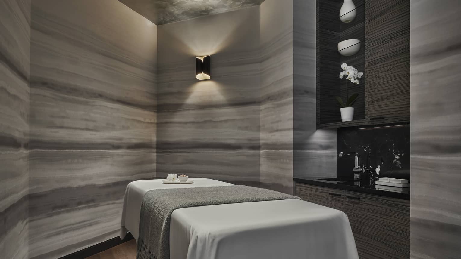 A dimly lit spa room with an empty spa table