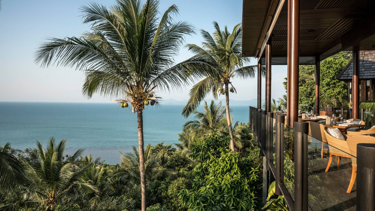 Corner patio dining room with glass balcony, high up on tropical mountain overlooking ocean