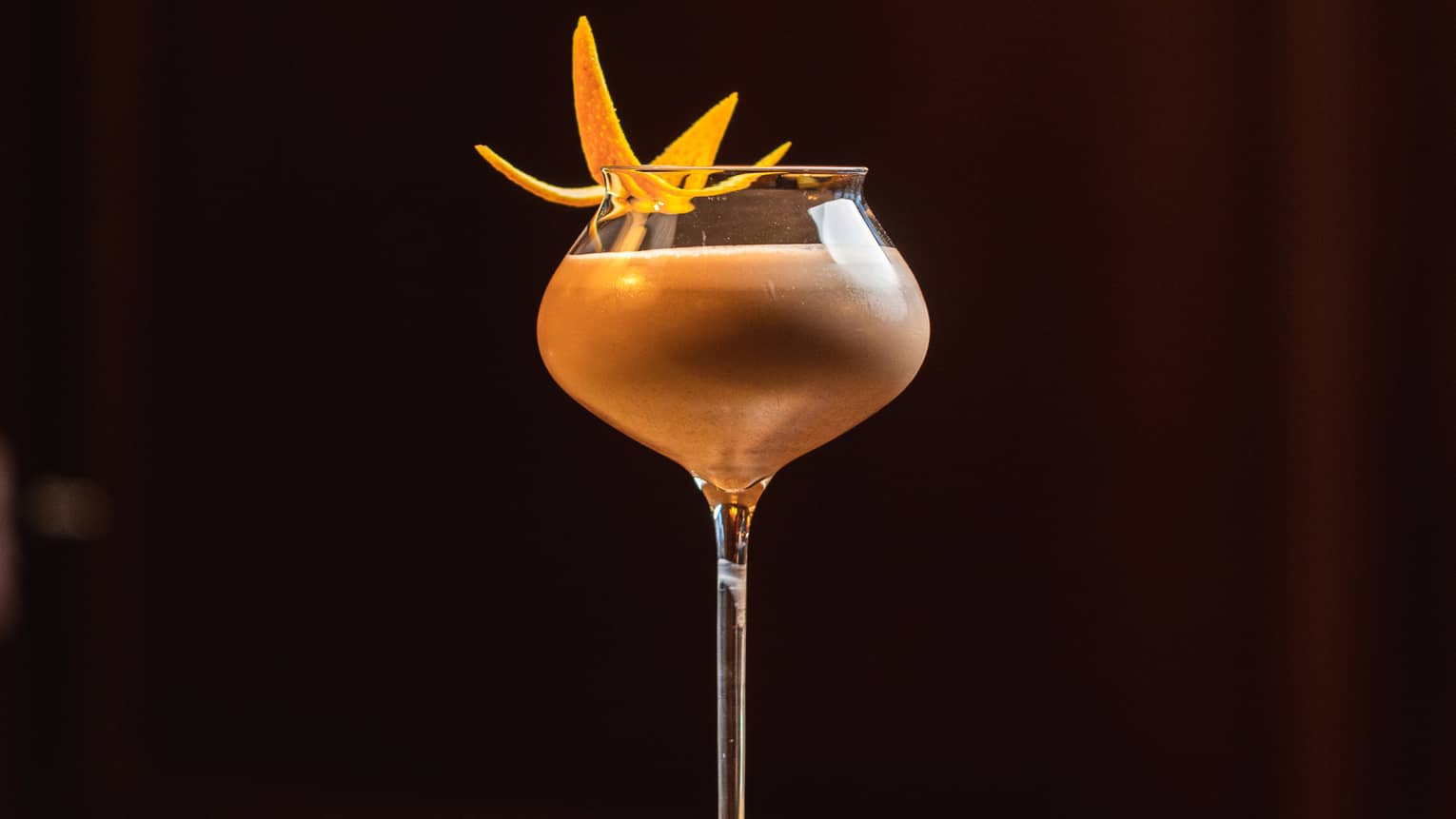 A cream coloured cocktail with a yellow garnish.