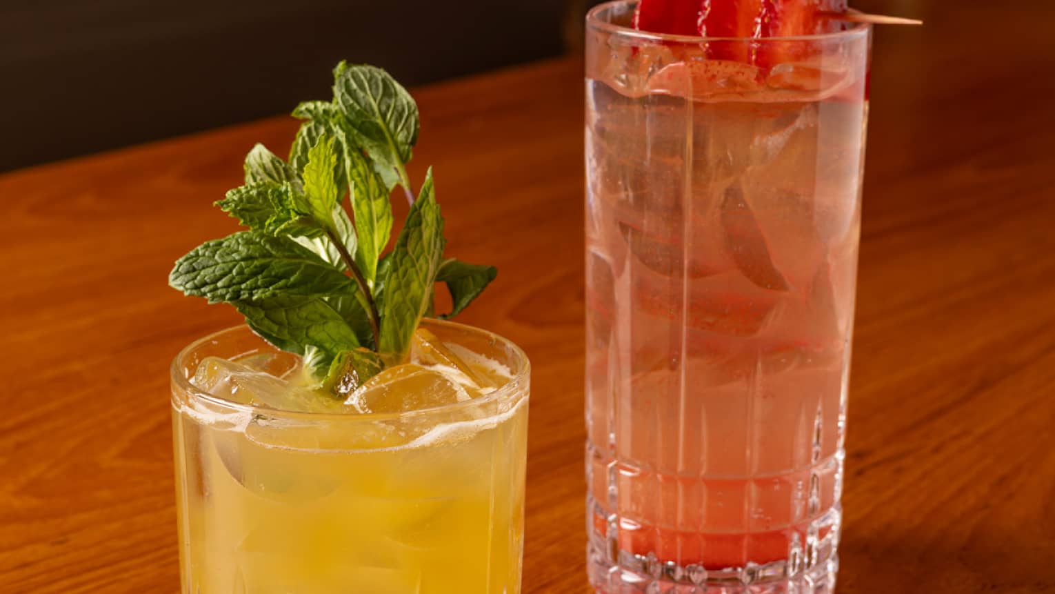 One yellow drink and one red drink placed beside each other on a dining table