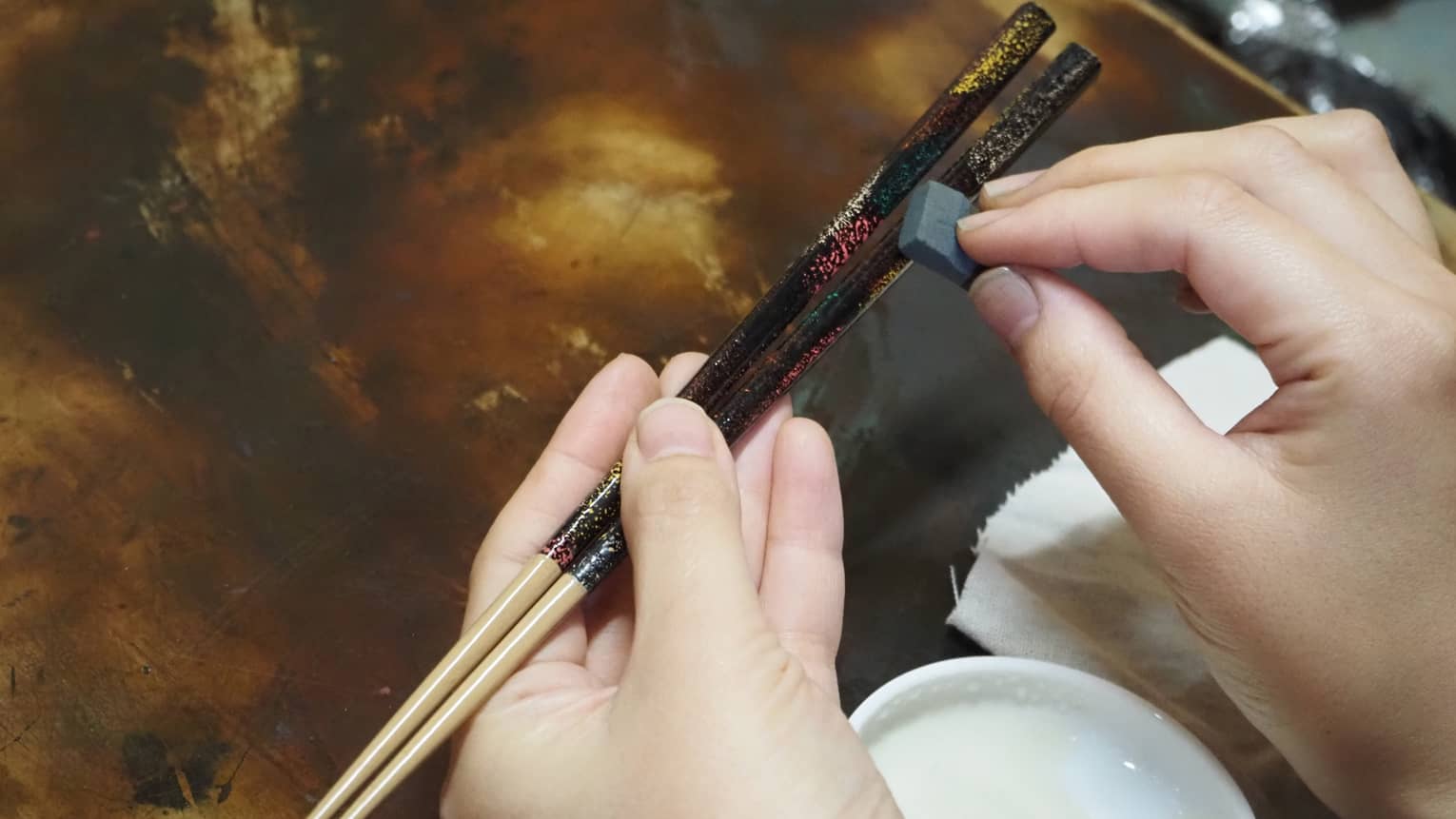 Hands apply Japanese lacquer to customize artisan chop sticks