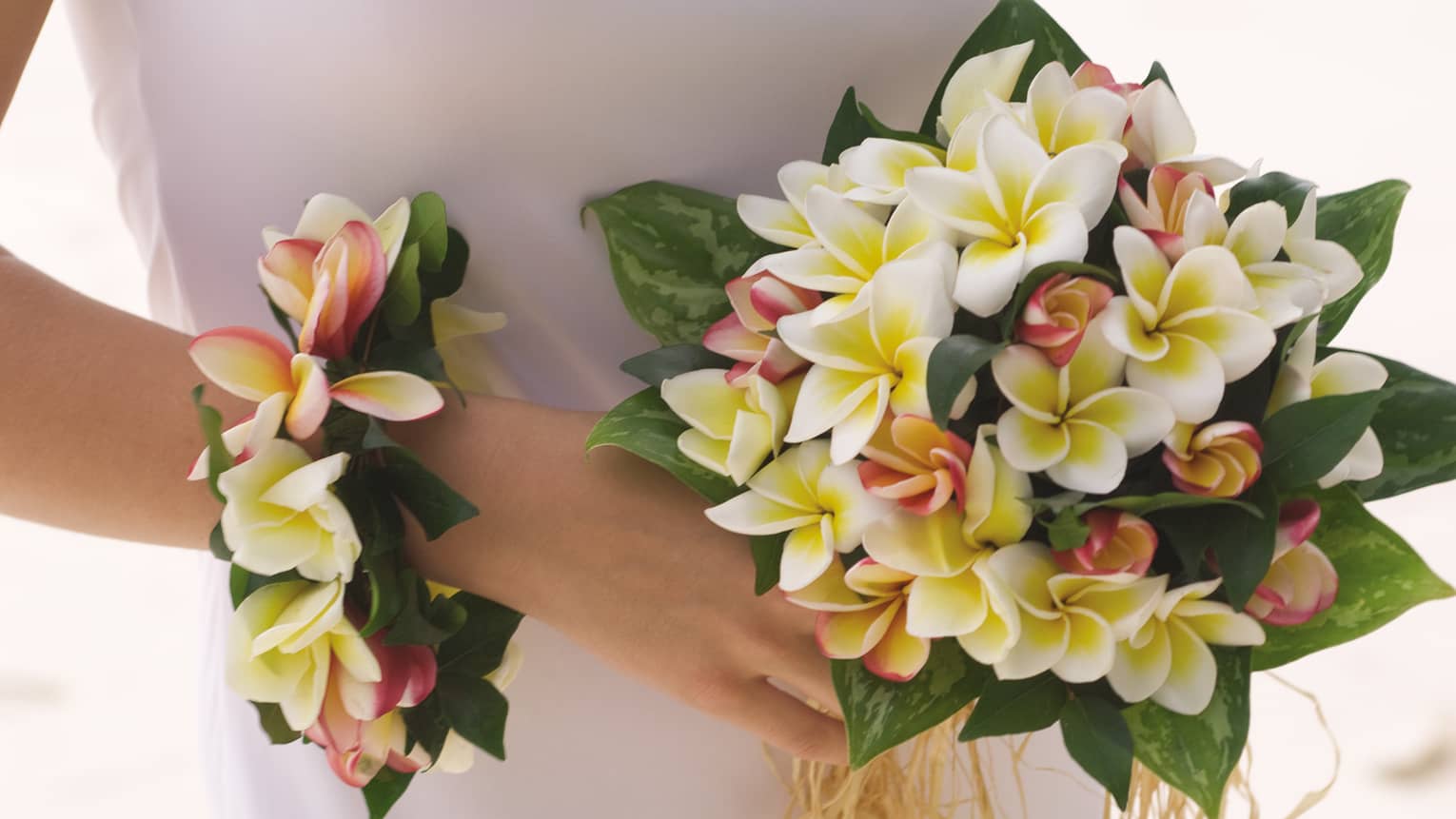Bride holding wedding bouquet and floral wristband with tropical flowers