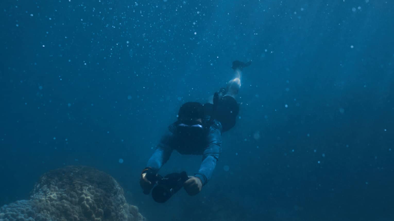Person diving beneath the water using dive scooter