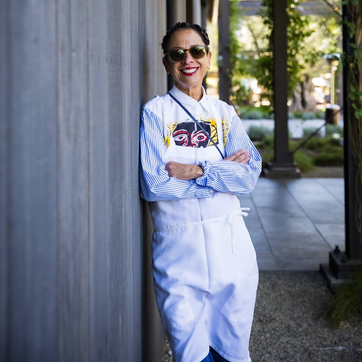 Nancy Silverton leaning against a building and wearing a chef?s coat.