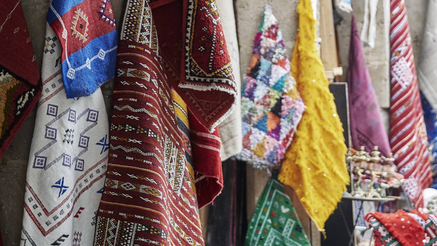 Onto archways hang woven textiles, each of multiple deep colours with geometric interlocking patterns and delicate accents.