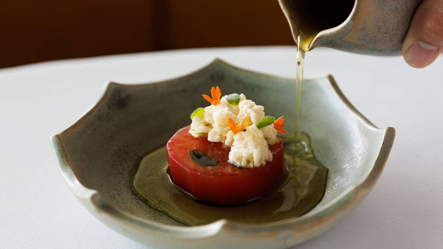 A tomato with oil being poured over it.