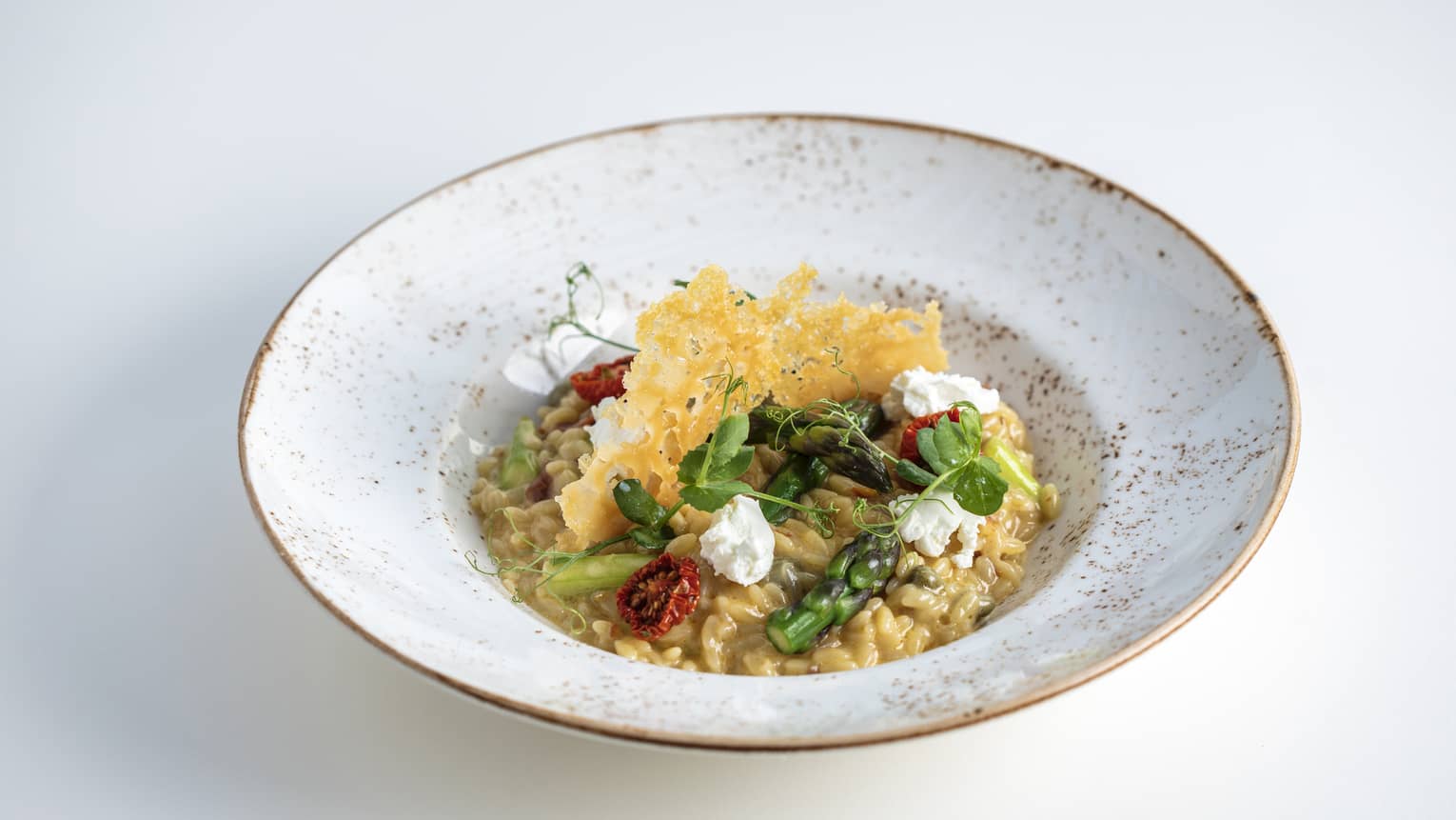 A grey bowl with vegetables and grains in it.