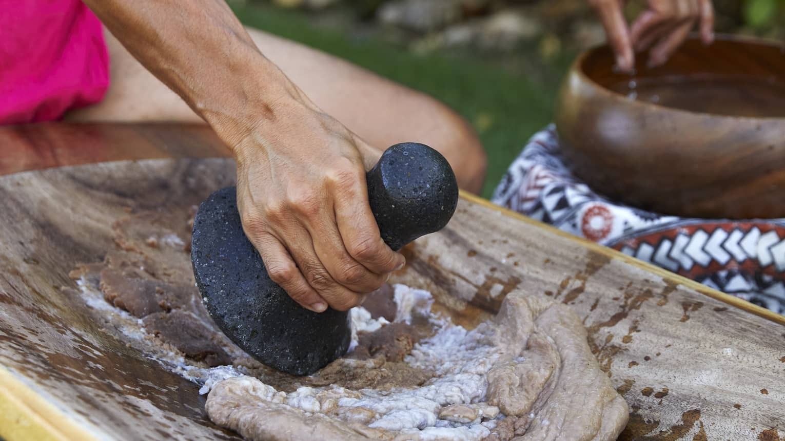 Native Hawaiian making poi on traditional board surface