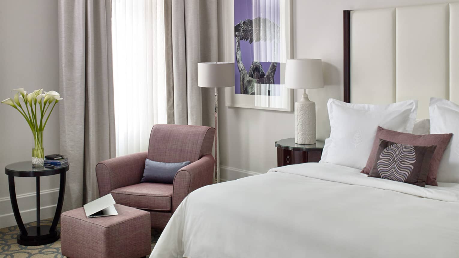 Gresham Room bed with white linens, pink armchair by window with long sheer white curtains