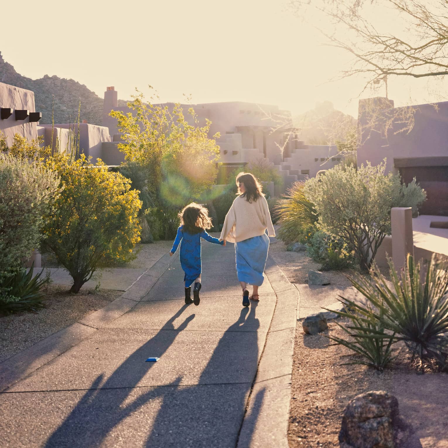 Woman and child walk down a path in the sunshine