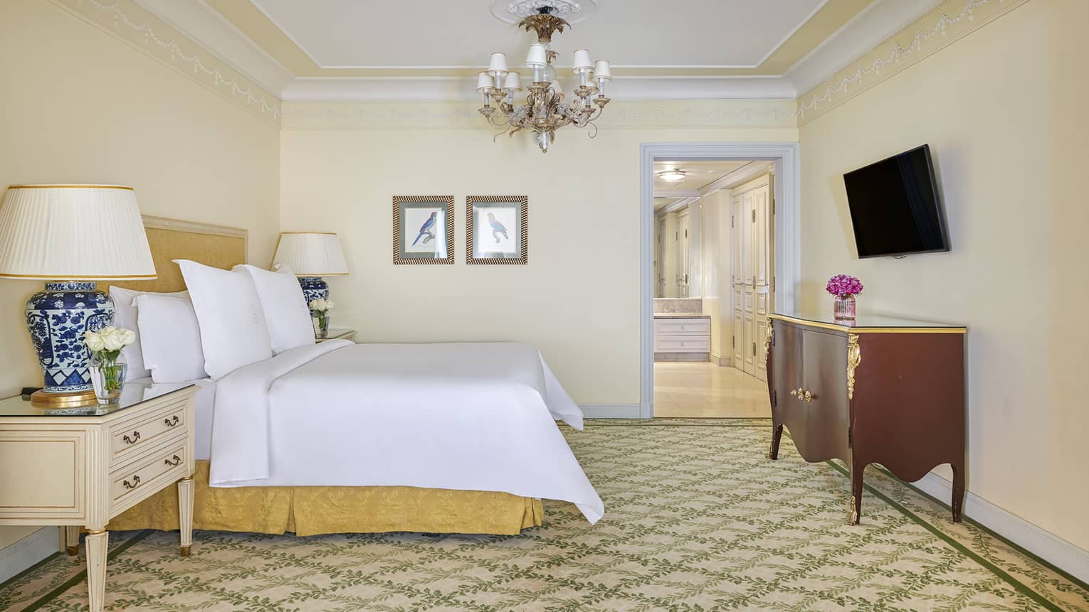 Deluxe Two Bedroom Suite bedroom with king bed, cherry sideboard, wall-mounted TV, door to hallway