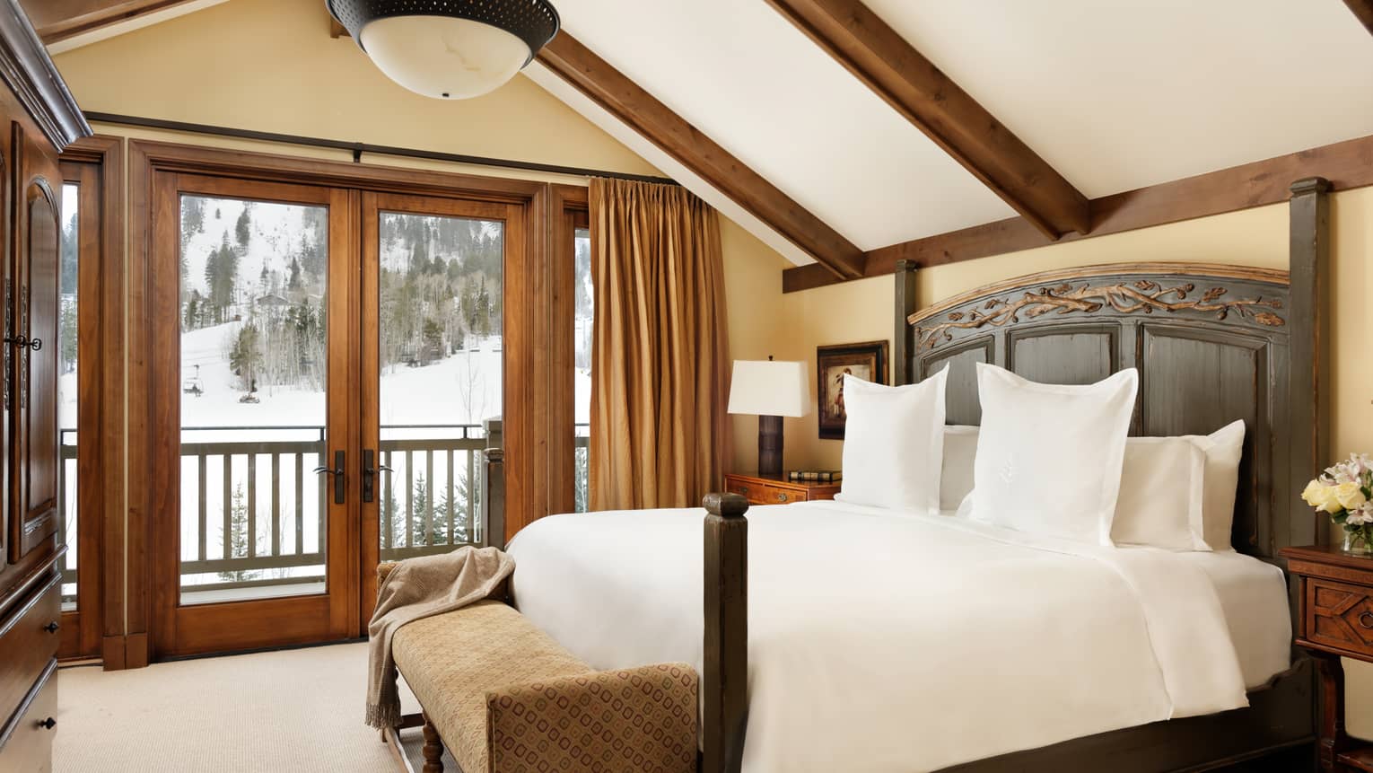 A white queen bed, wooden headboard, walk-out deck, wood trim