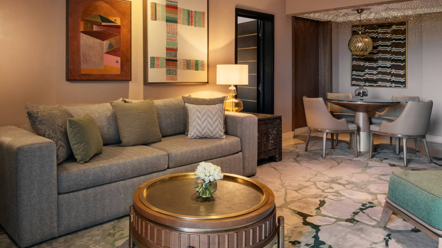 Living room with grey sofa, round coffee table and a dining table with four chairs