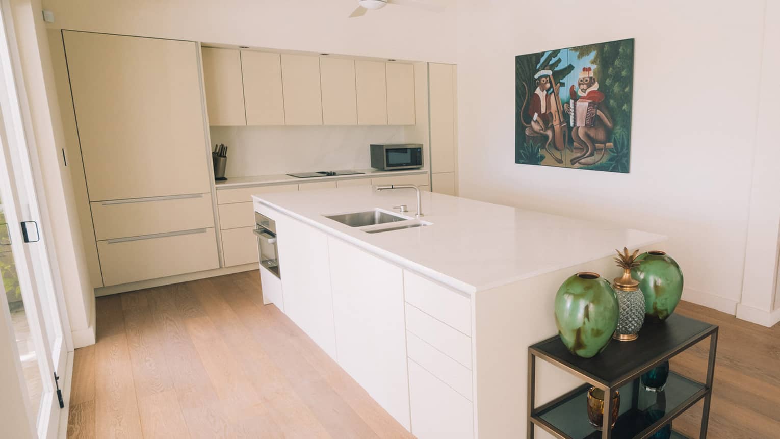 Kitchen with white cupboards, island and countertop. Wooden floors.