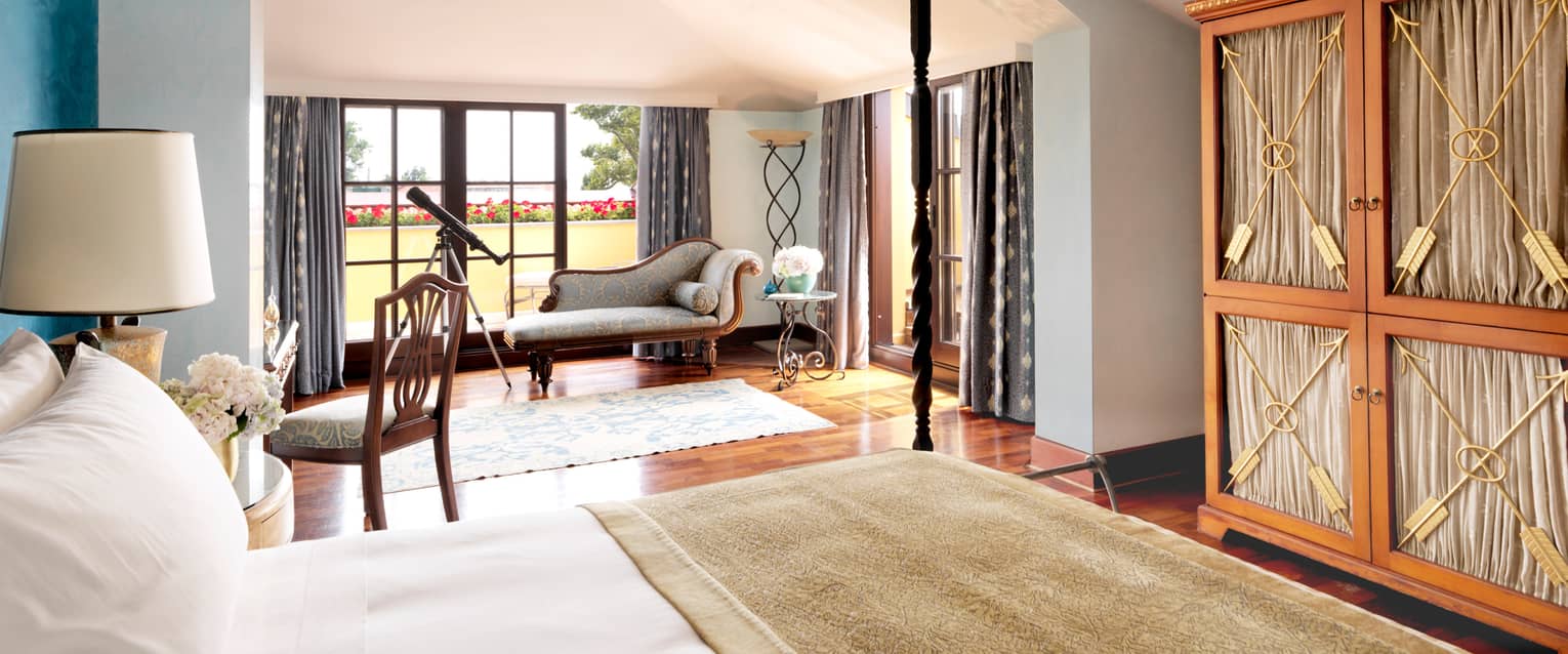 Marmara Suite bright hotel room with bed, antique-style chase, telescope at sunny window