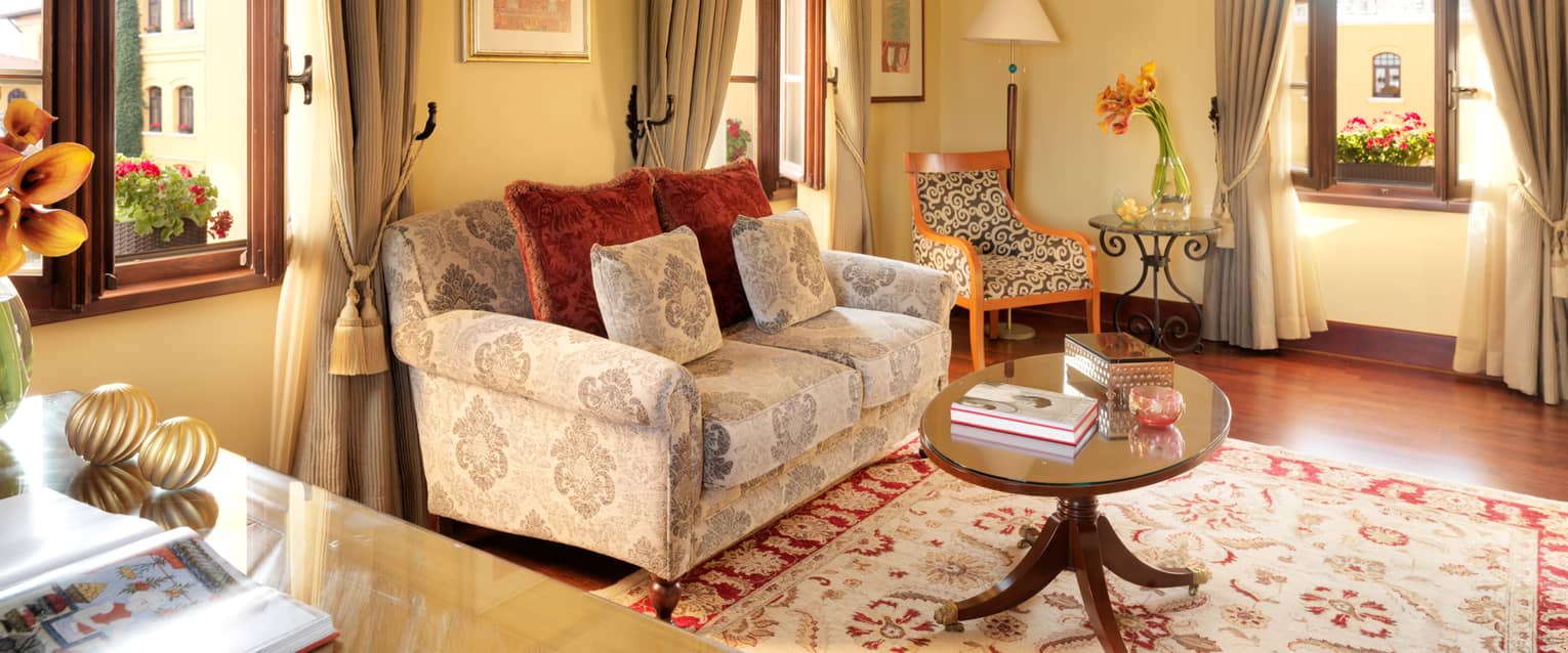 Patterned loveseat between two tall windows in One-Bedroom Suite