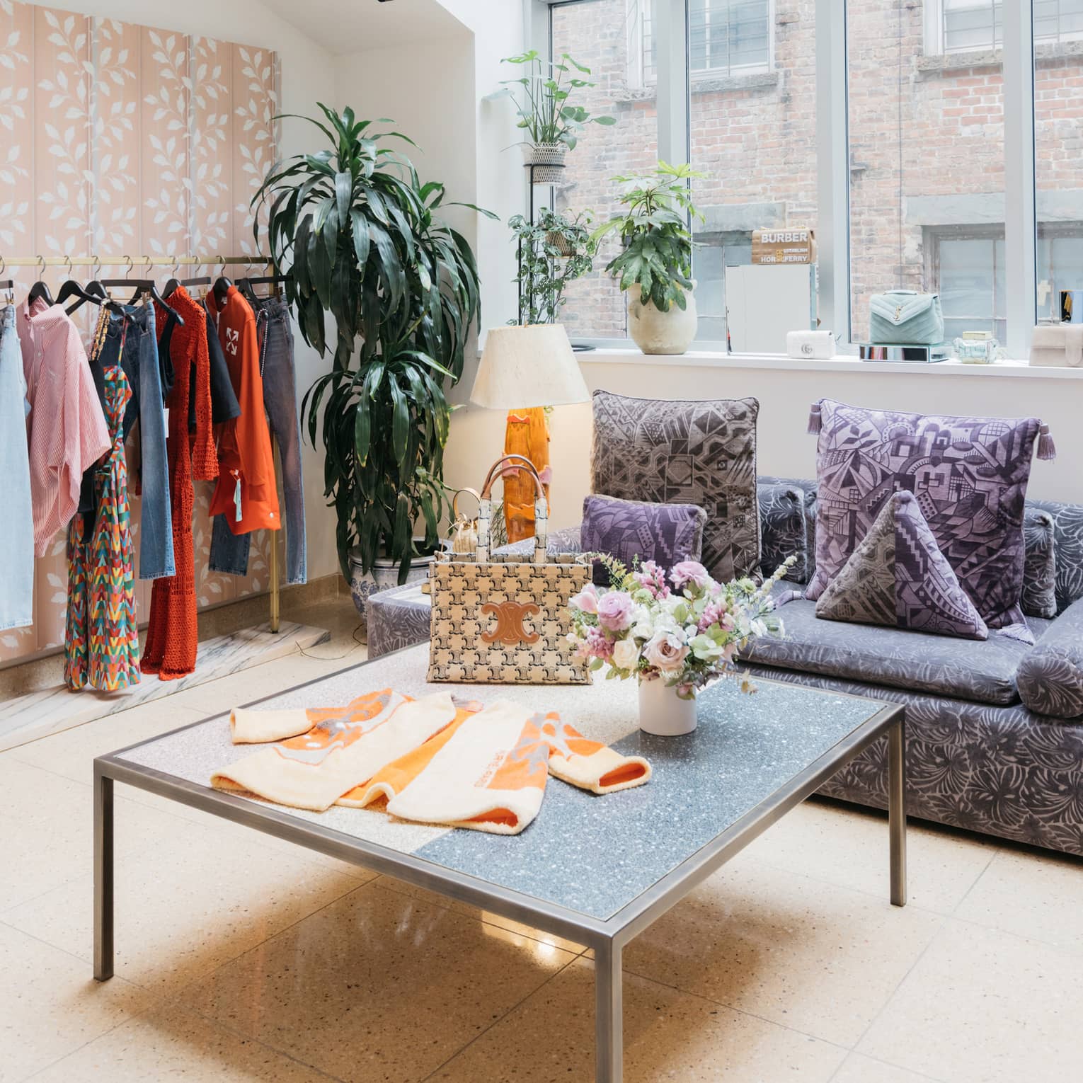 Clothes on a table and hanging near large windows.