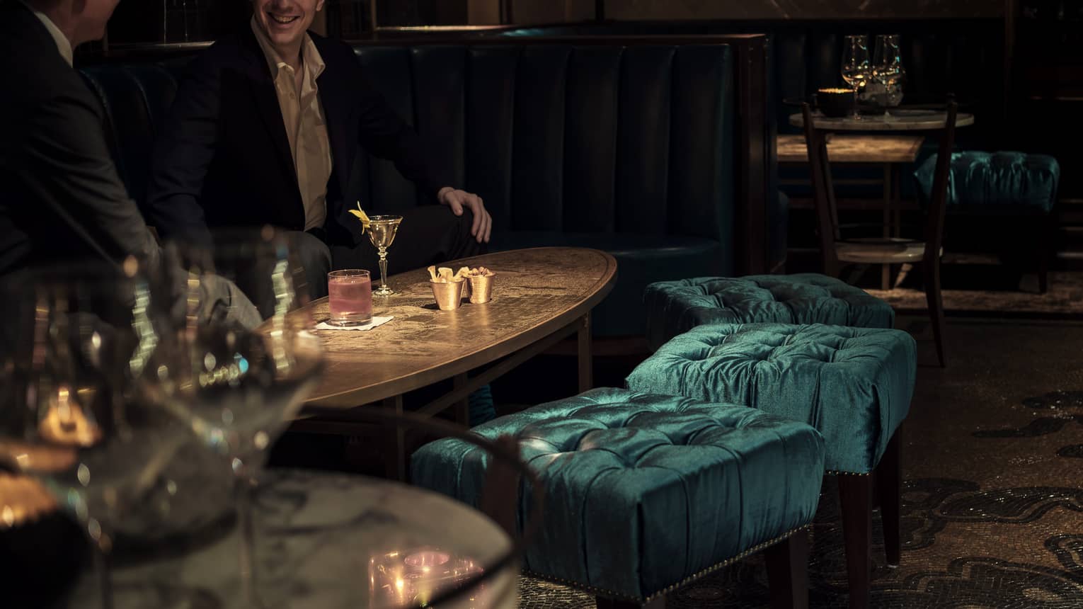 Close-up of men drinking cocktails on lounge table in dimly-lit Charles H dining room