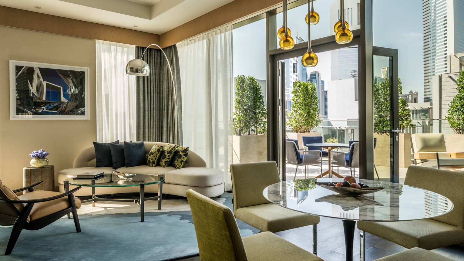 Modern hotel suite living room sofa, glass tables and chairs, open glass door to patio