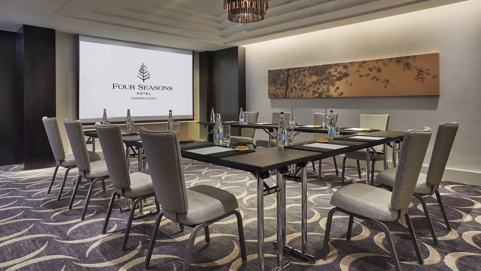 Business meeting room with large screen with Four Seasons logo, tables and chairs