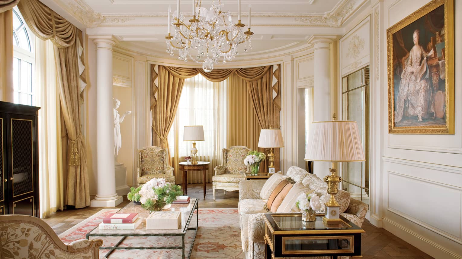 Elegant Royal Suite living room with cream floral sofas and decor, crystal chandelier, white statue, large oil painting
