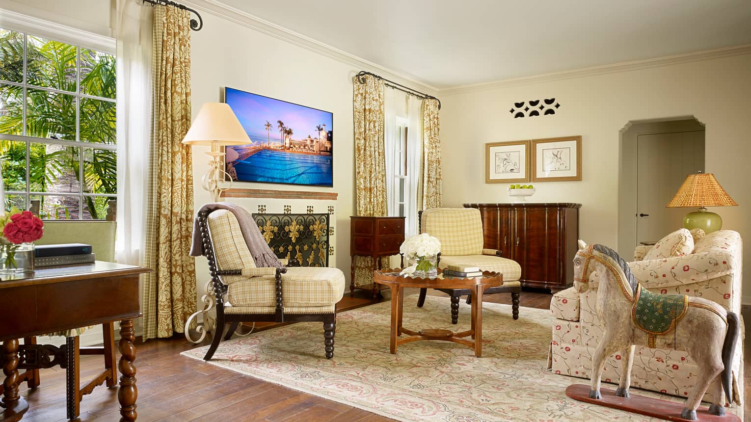 Bungalow Suite sunny living room with yellow plaid accent chairs, floral sofa, rocking horse statue