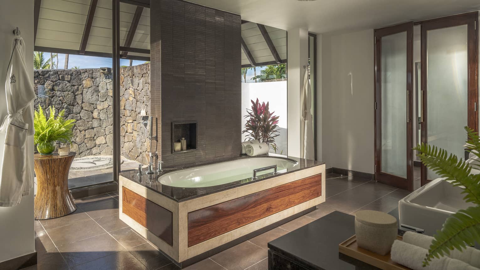 Large bathroom with wooden-framed tub, walk-out stone terrace