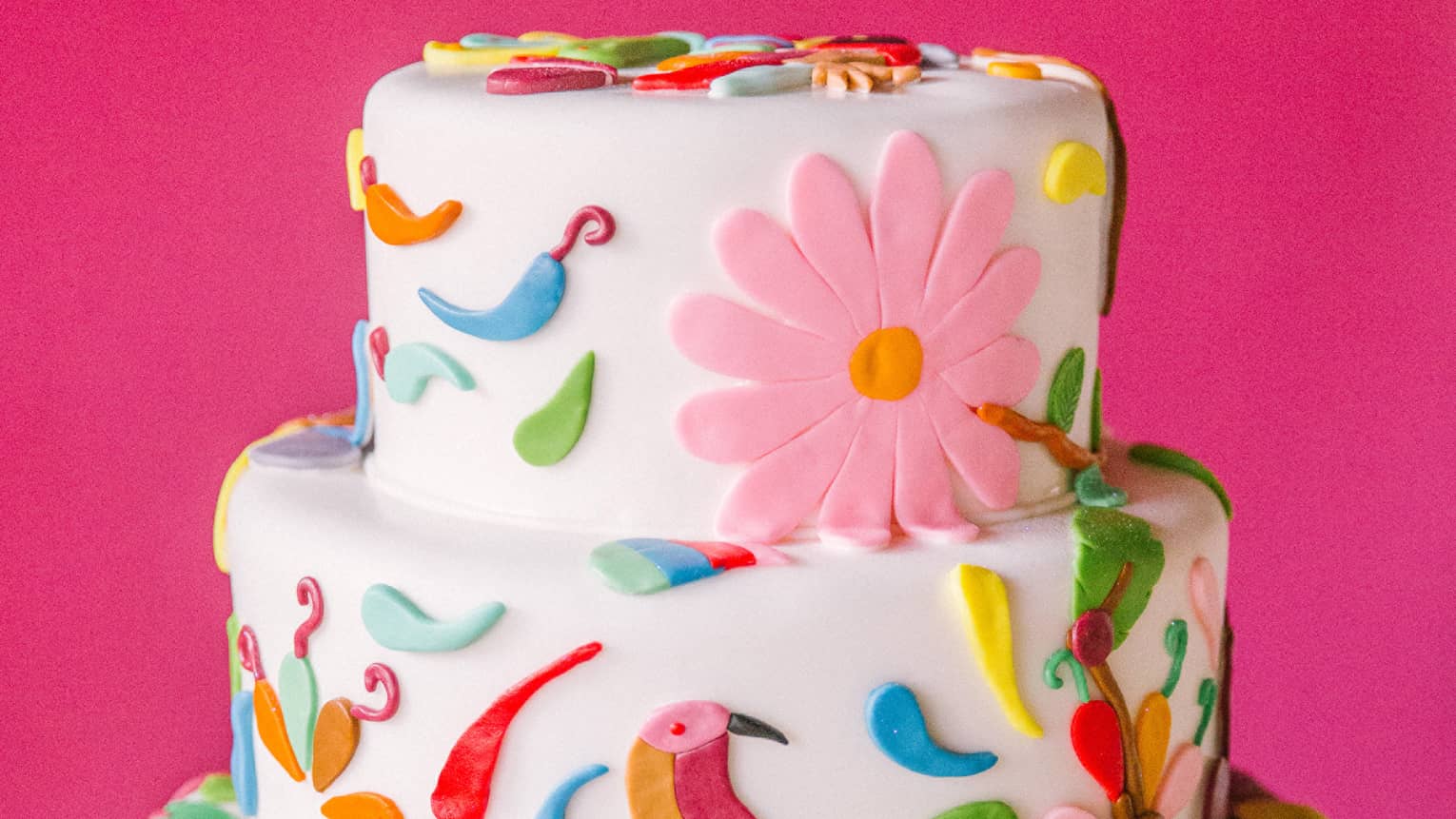 Three tiered wedding cake decorated with colourful icing birds, flowers