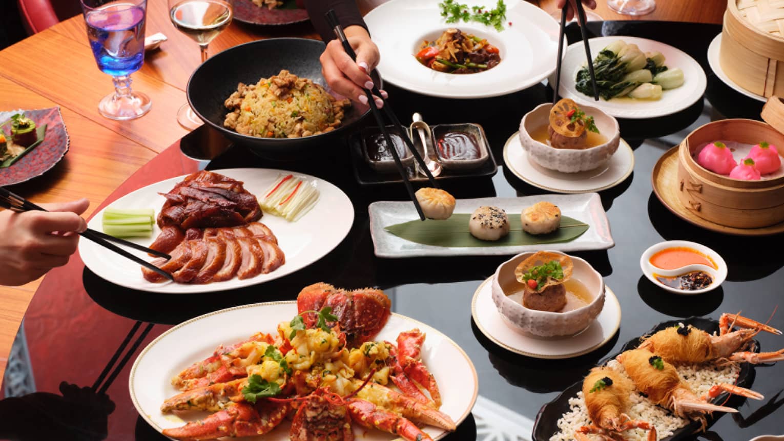 Round dining table with various dishes that people share, including meat and fried shellfish