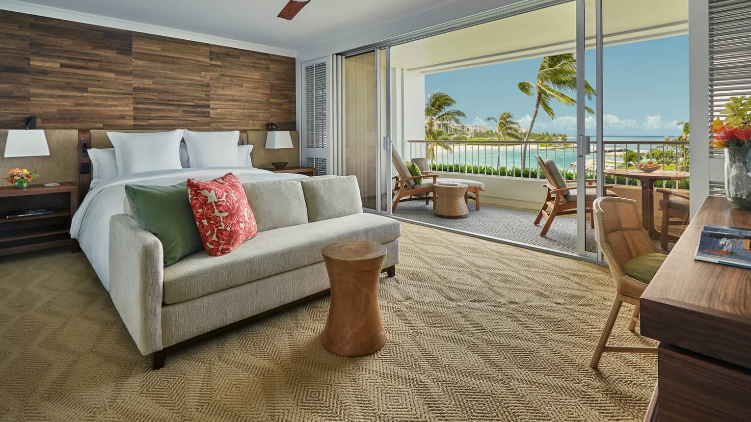 Prime Corner Oceanfront Room loveseat at foot of bed against wood grain wall, balcony wall