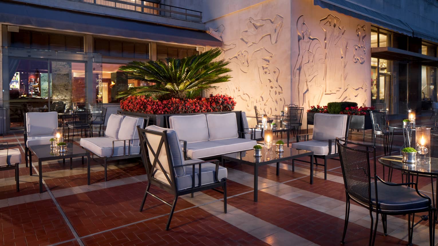 Ritz Bar outdoor patio lounge at night with cushioned chairs and loveseats around candle-lit cocktail tables