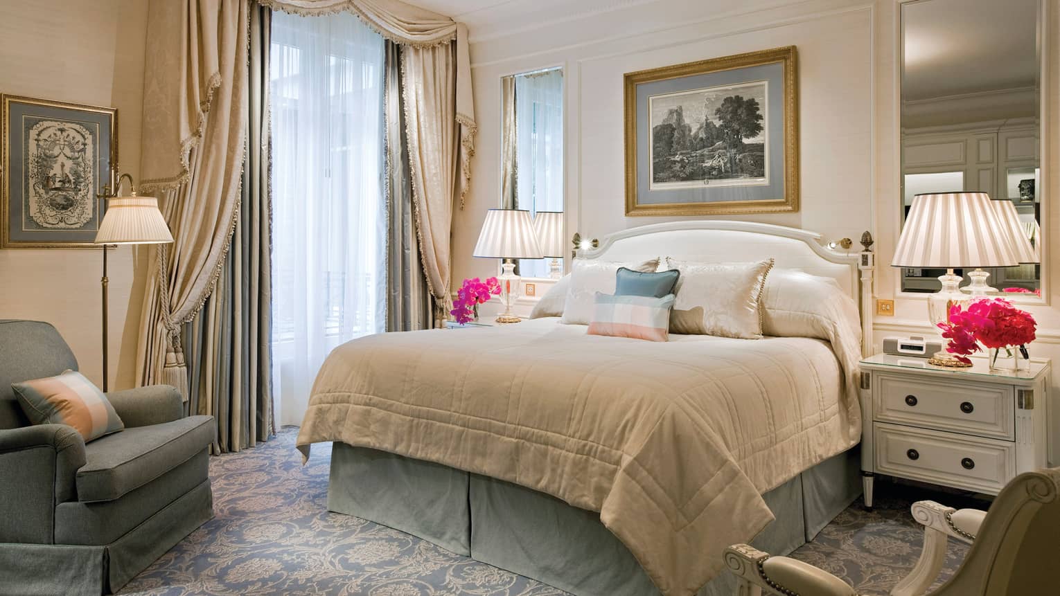 Hotel suite bed with silk pillows, flanked by mirrors, lamps, elegant curtains over windows