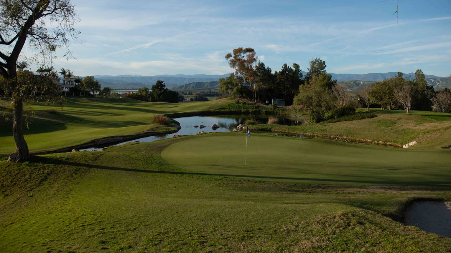 Golf course green with a water feature in the near distance