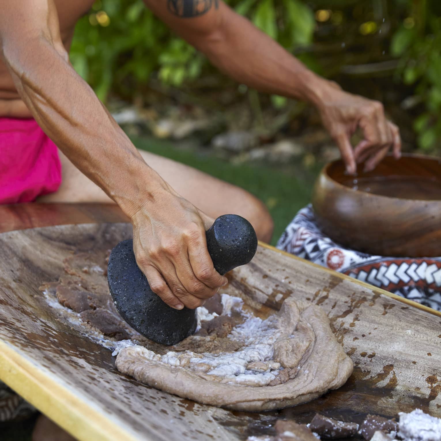Native Hawaiian making poi on traditional board surface