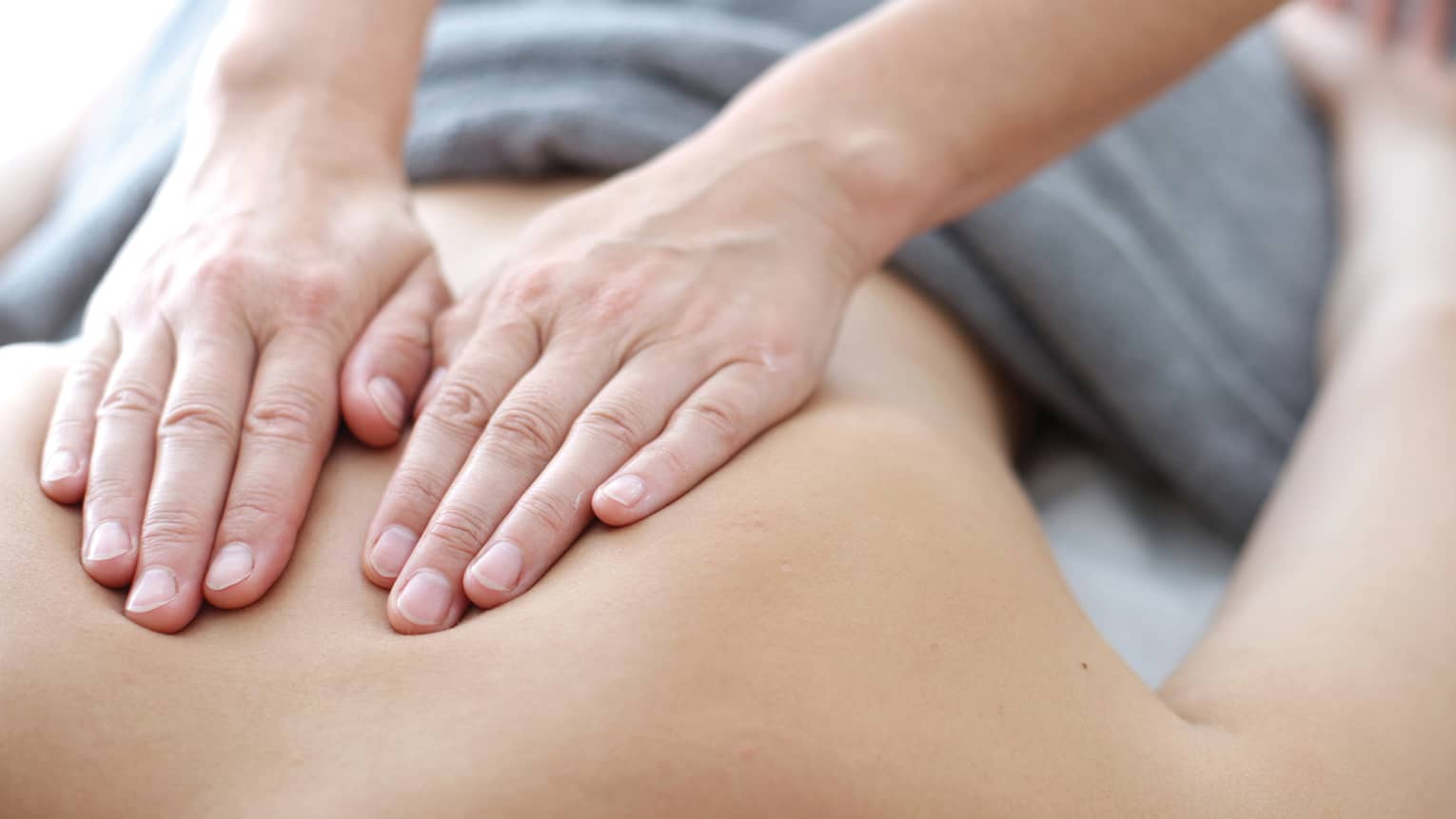 Hands massaging bare shoulders, back