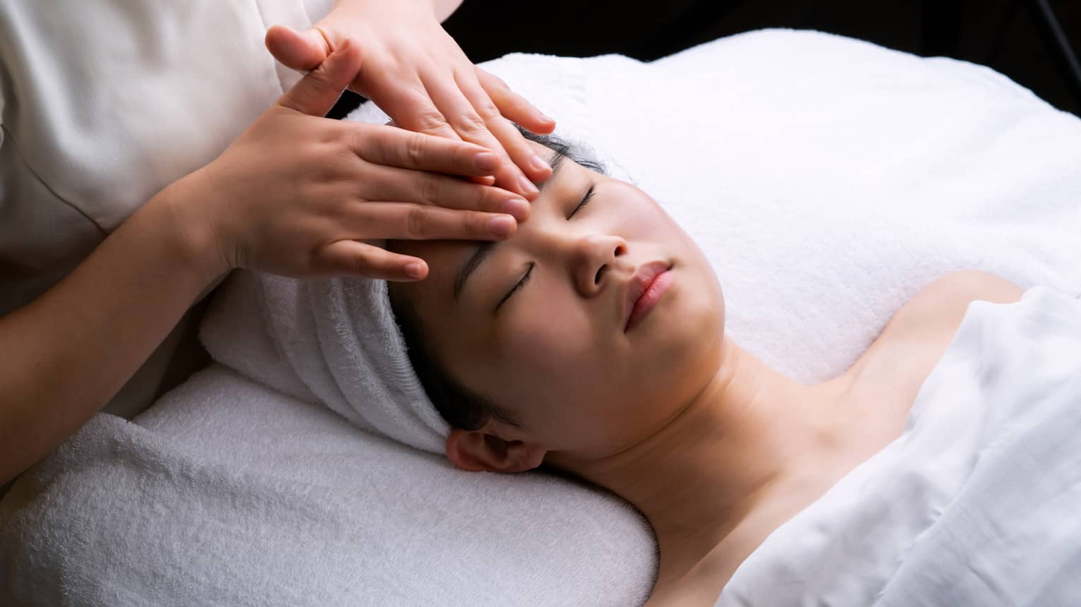 Spa staff places hands on woman's forehead during Anti-Oxidant Facial