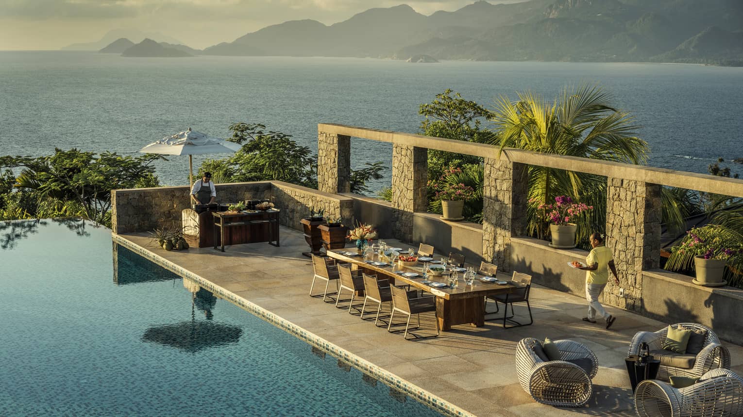 Aerial view of Four-Bedroom Residence Villa private deck with 8-person dining table beside pool, ocean view