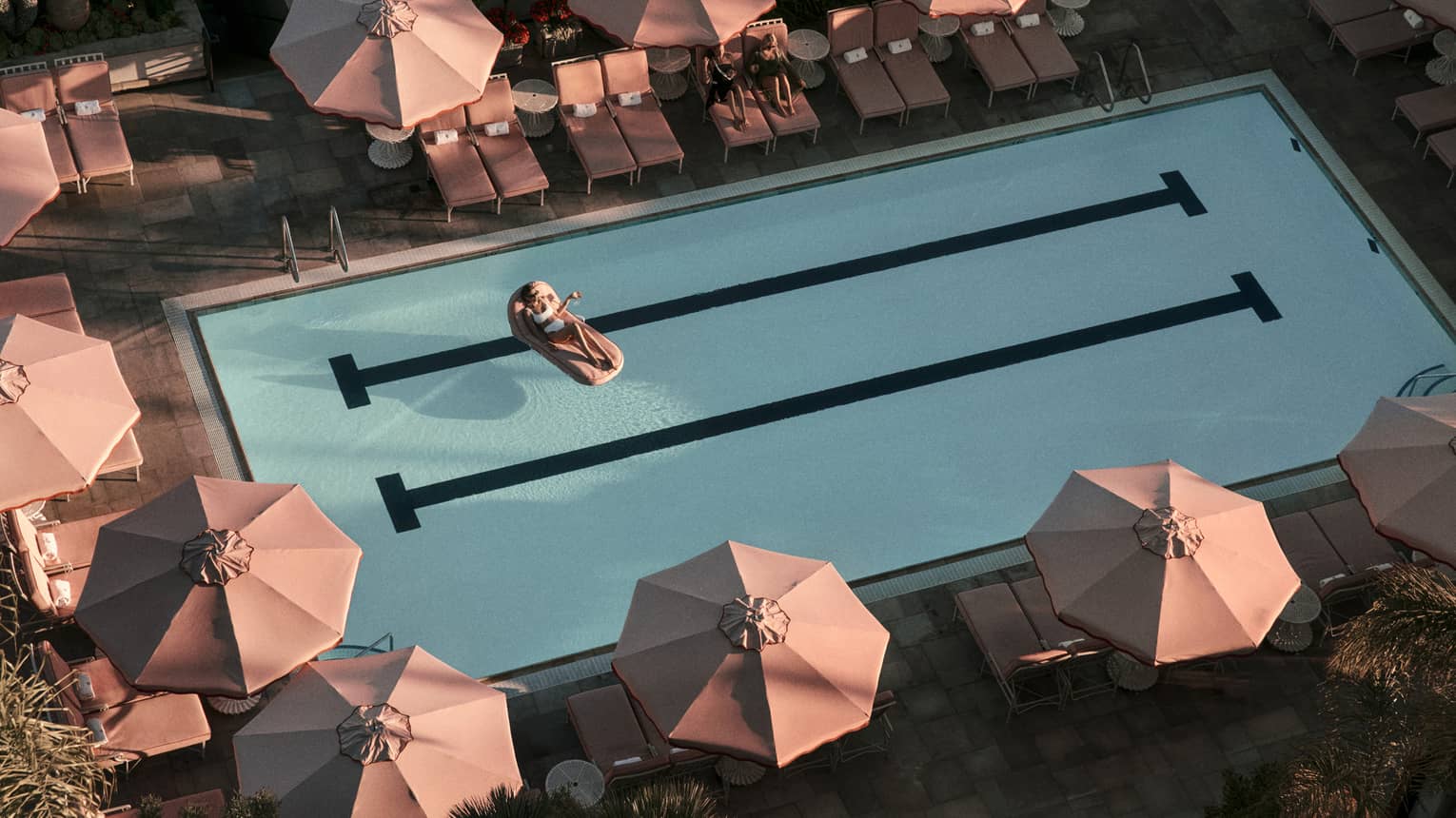 Hotel pool surrounded by pink umbrellas