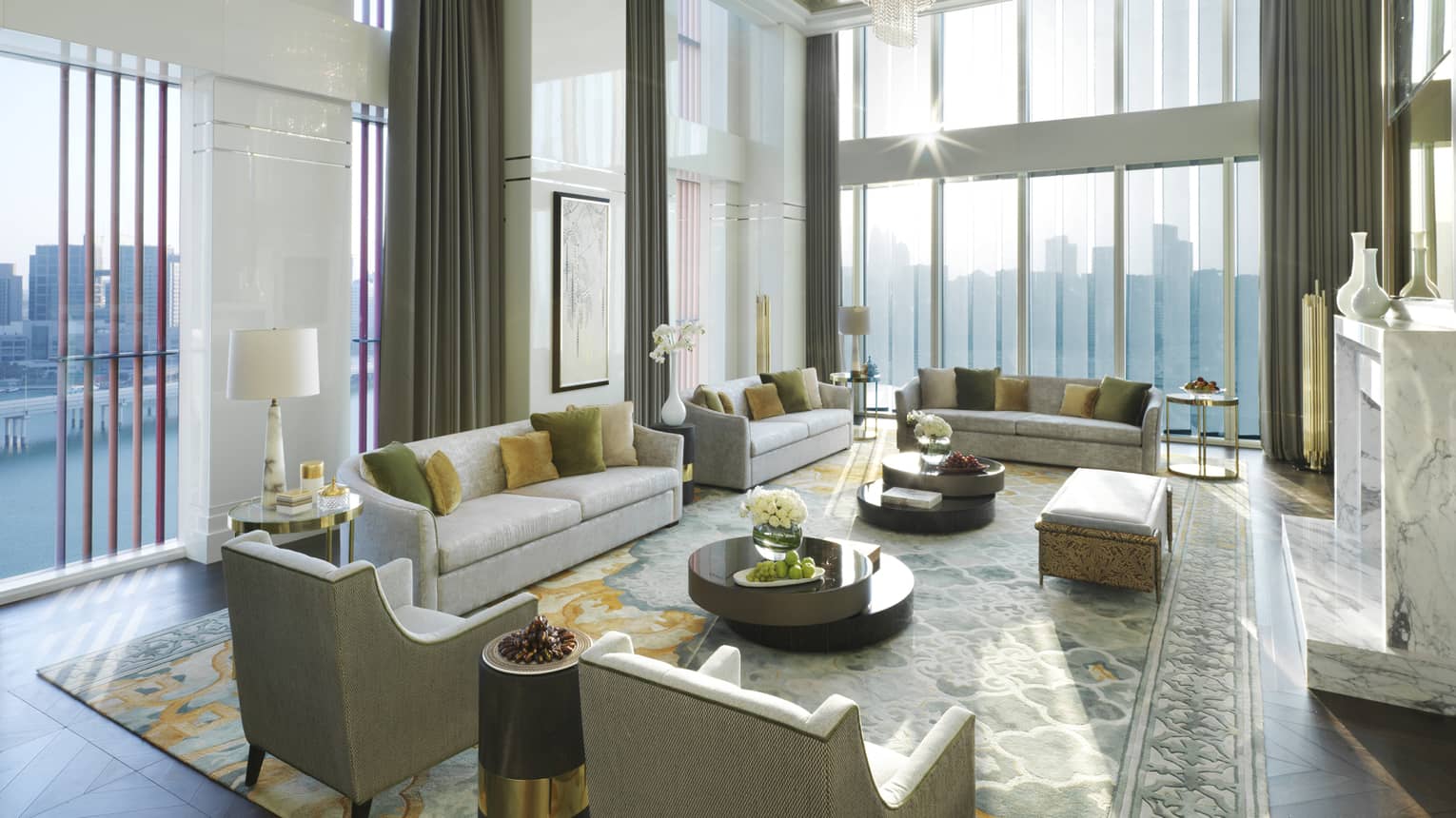 Royal Suite with high dome ceiling, modern crystal chandelier, sunny living room with several sofas and chairs, area rug