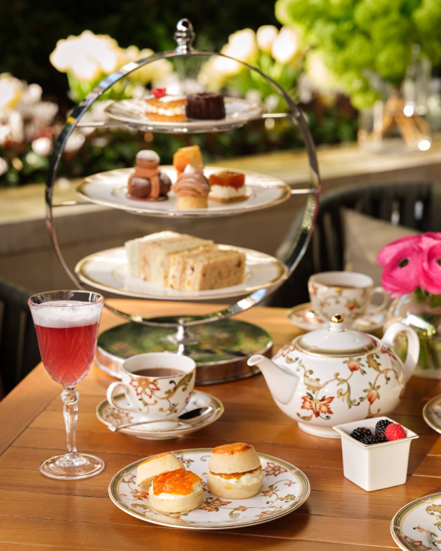 Afternoon tea service with floral teapot, cups, desserts on tiered tray