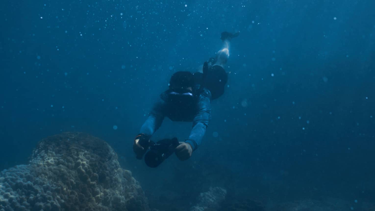 Person diving beneath the water using dive scooter