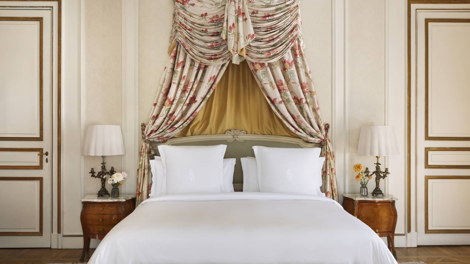 King bed with white linens and a canopy-style headboard made from floral fabric