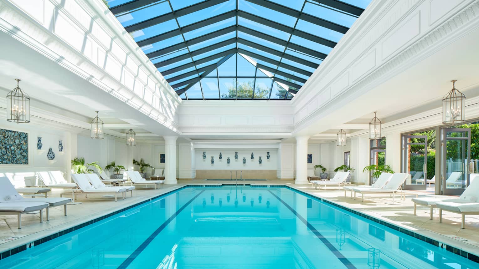 Indoor pool with lounge chairs and ceiling with windows.
