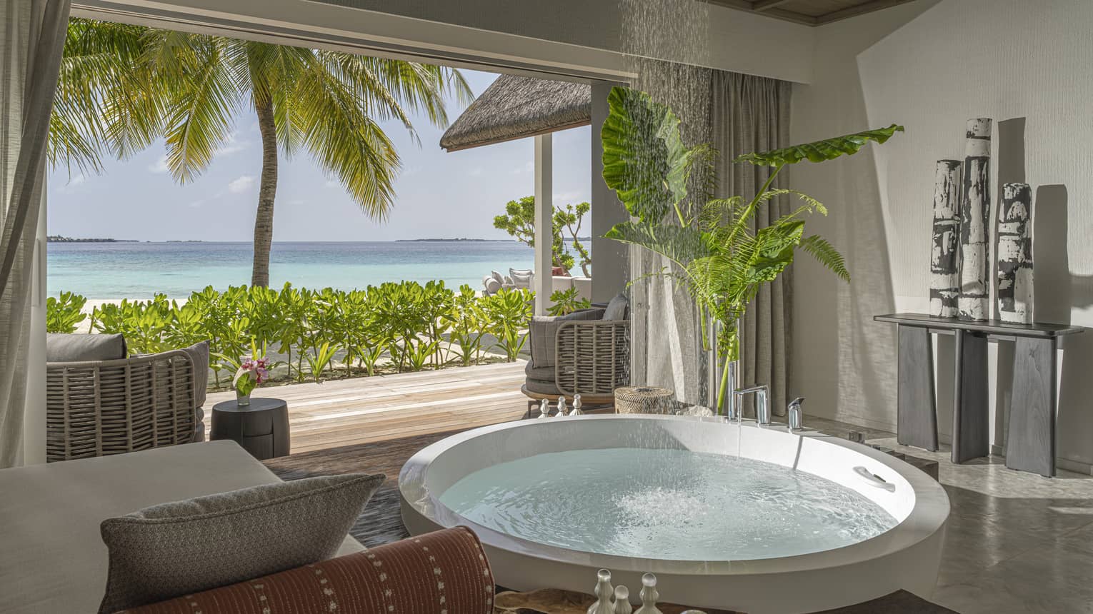 Large luxury bathroom with a circular tub opening to a tropical beachfront deck