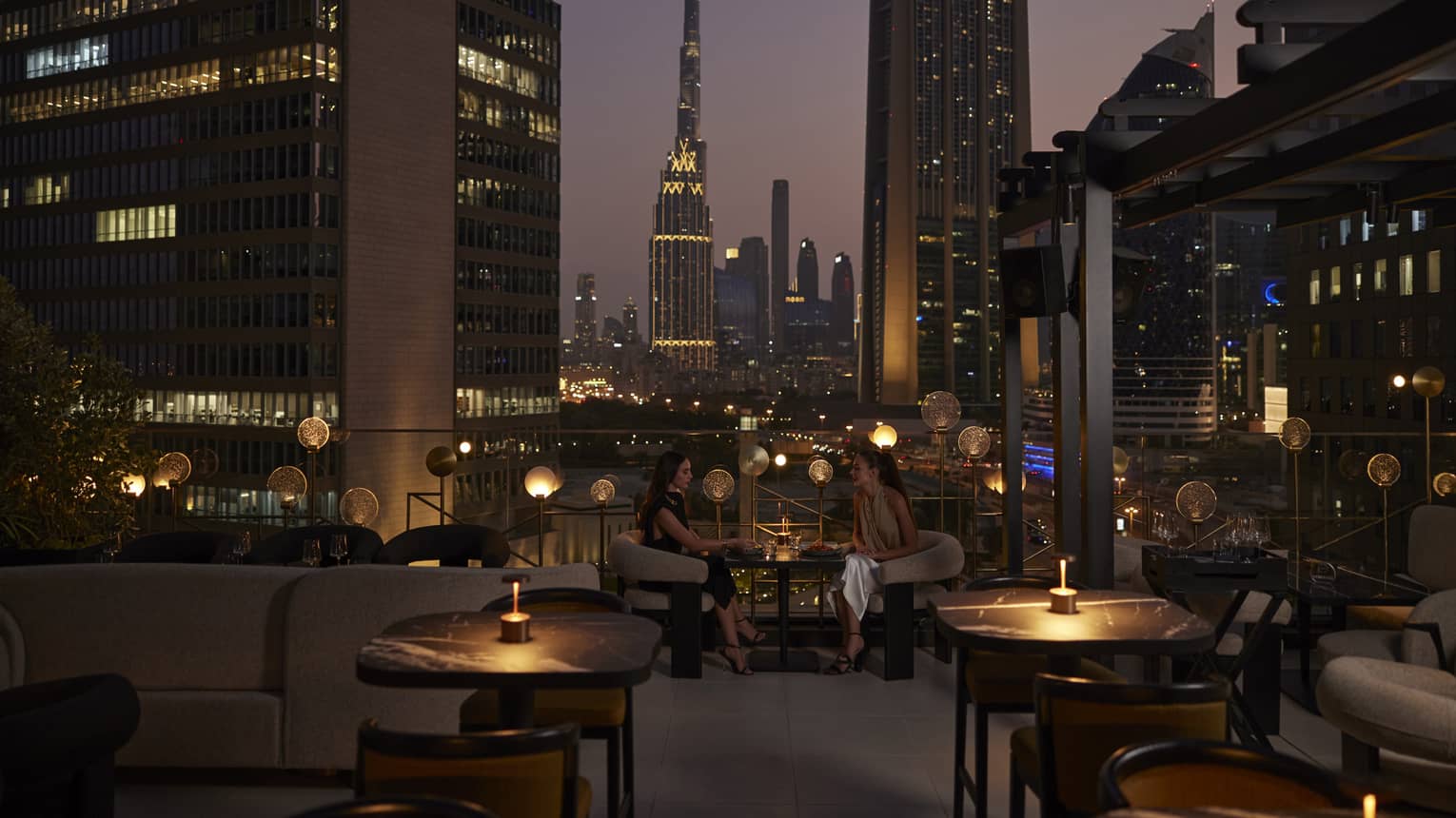 Nightime view of rooftop lounge with Dubai skyline in background