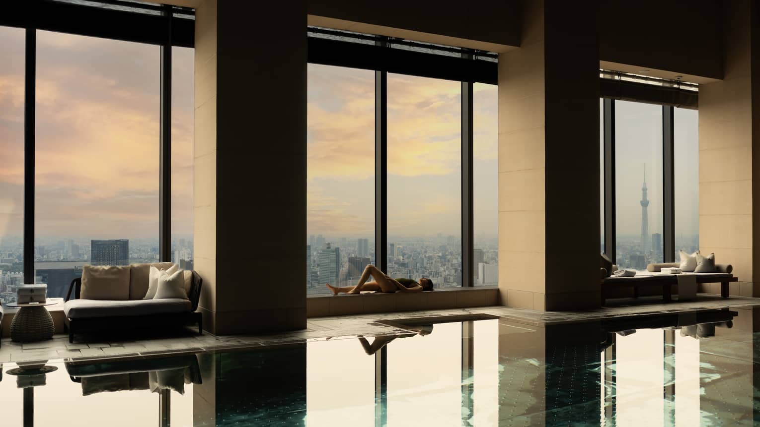 Indoor hotel pool with wall of windows overlooking city